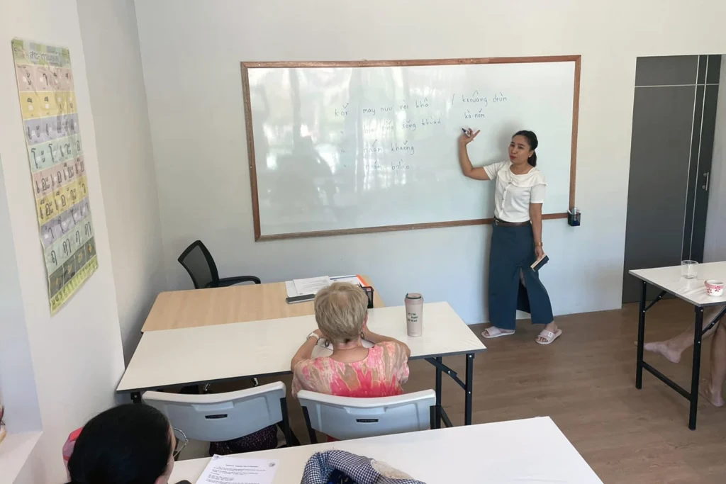 A Thai language teacher explaining a lesson at the whiteboard