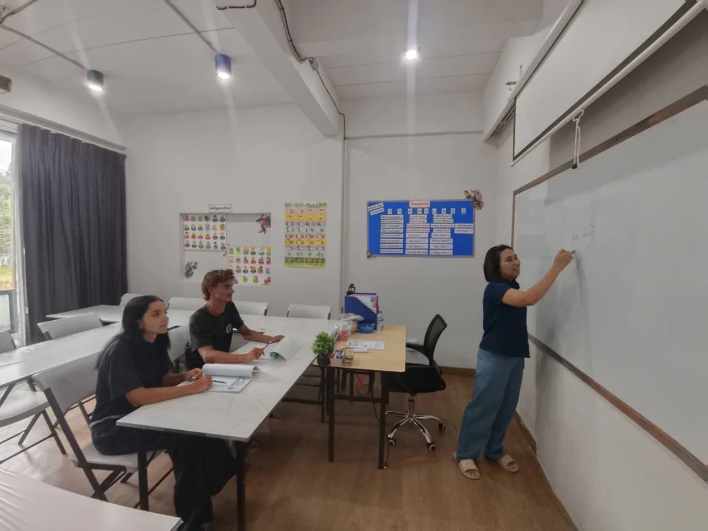 A Thai language teacher explaining a lesson at the whiteboard