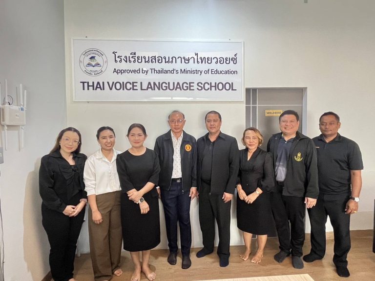 Group posing beneath the Thai Voice Language School sign